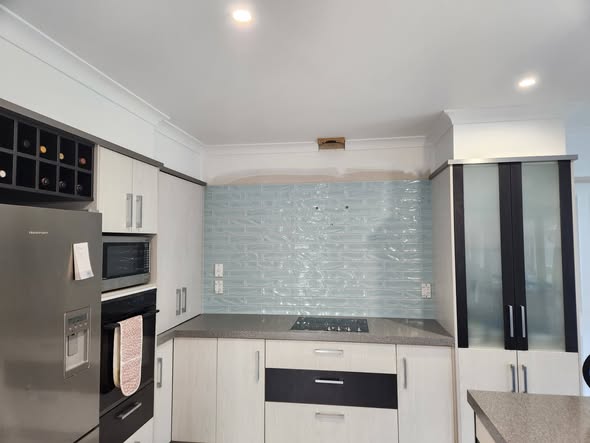 Grey-blue brick splashback alongside stainless fridge