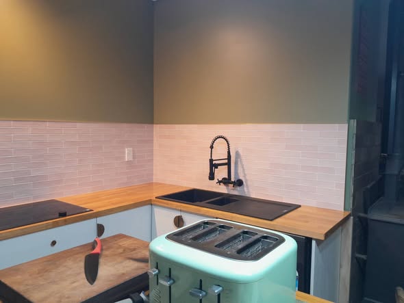 Pearl handmade-look subway splashback above butcher-block benchtop with mint Smeg toaster and matte black tapware