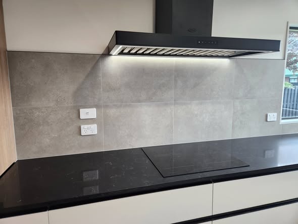 Slate grey large-format tile splashback with black rangehood